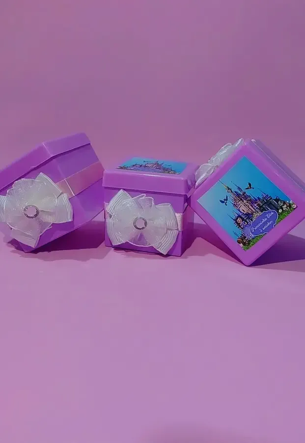 Caixinhas de lembrancinha roxas com laço branco e tema de princesa